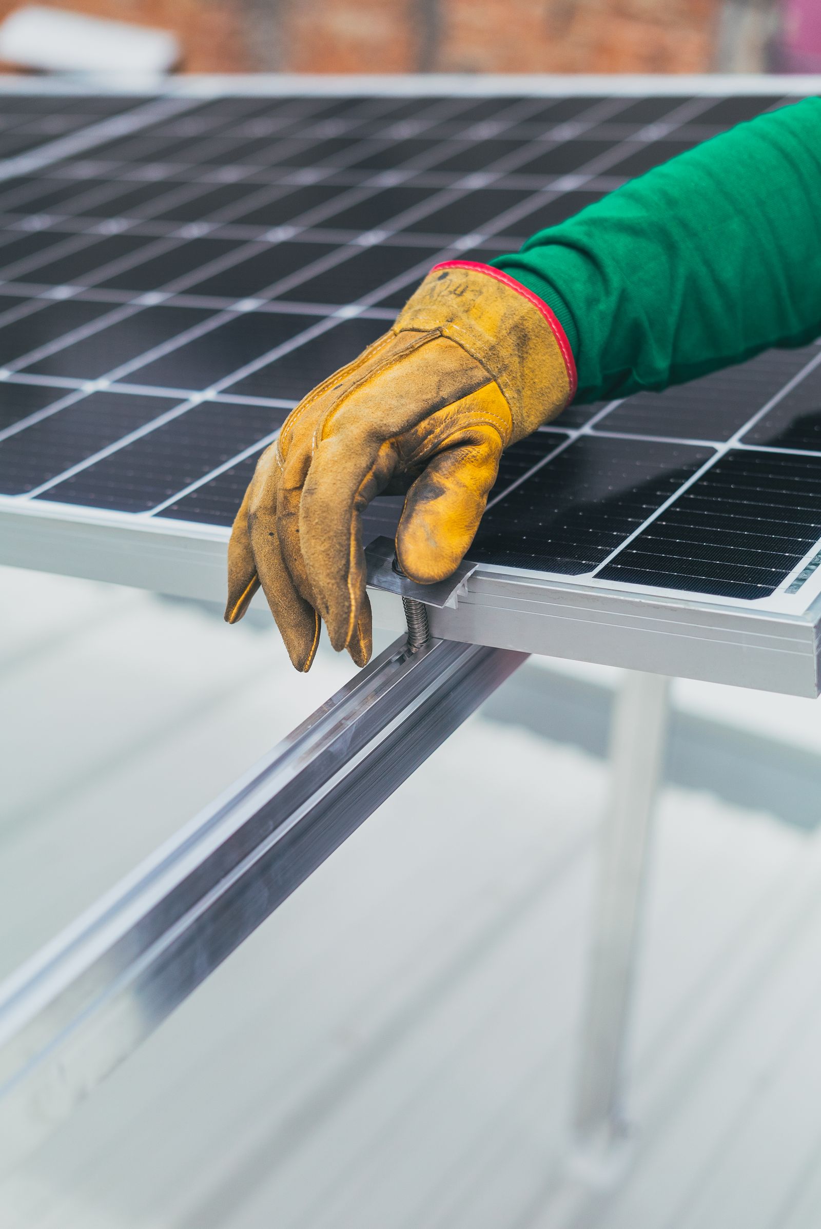 Mano con guante de protección ajustando un panel solar